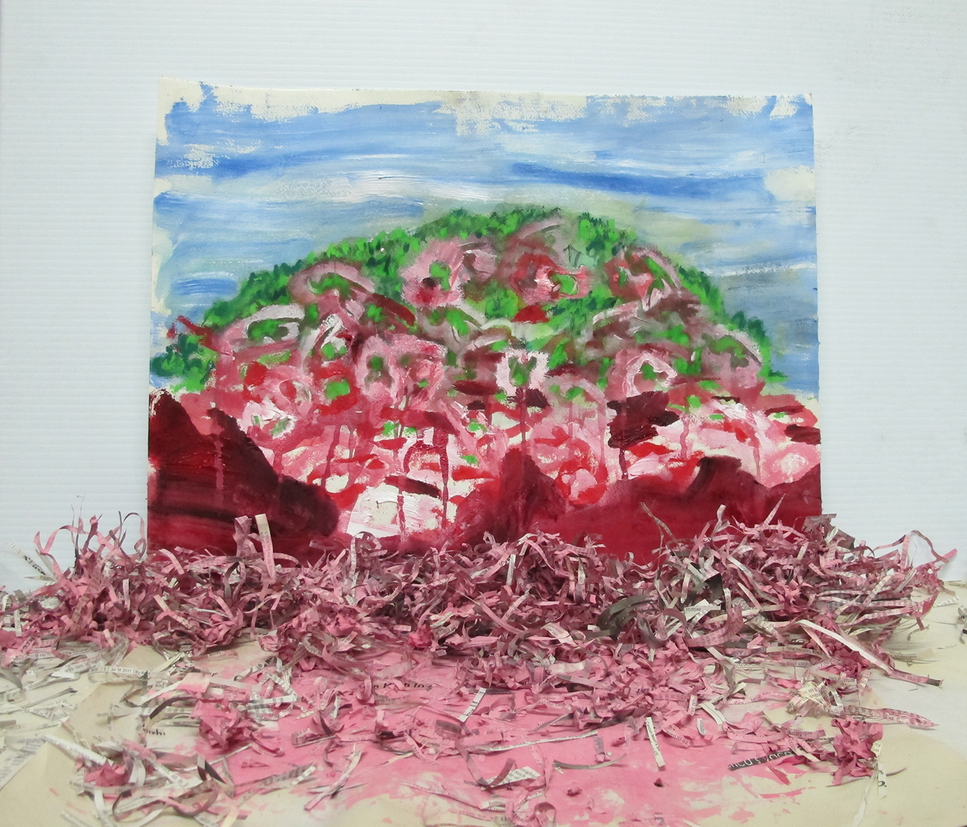 An abstract landscape with blue sky and shredded pink, red and green land
