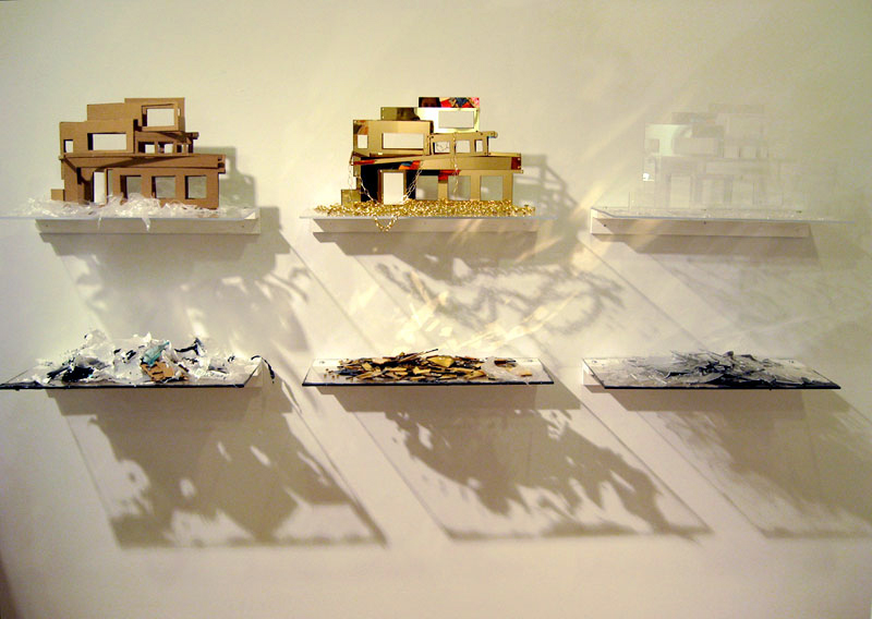Sculpture wall installation of six shelves with three abstract modern houses in different materials displayed on them