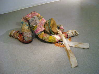 A prone figure made out of strips of rags used for cleaning palettes